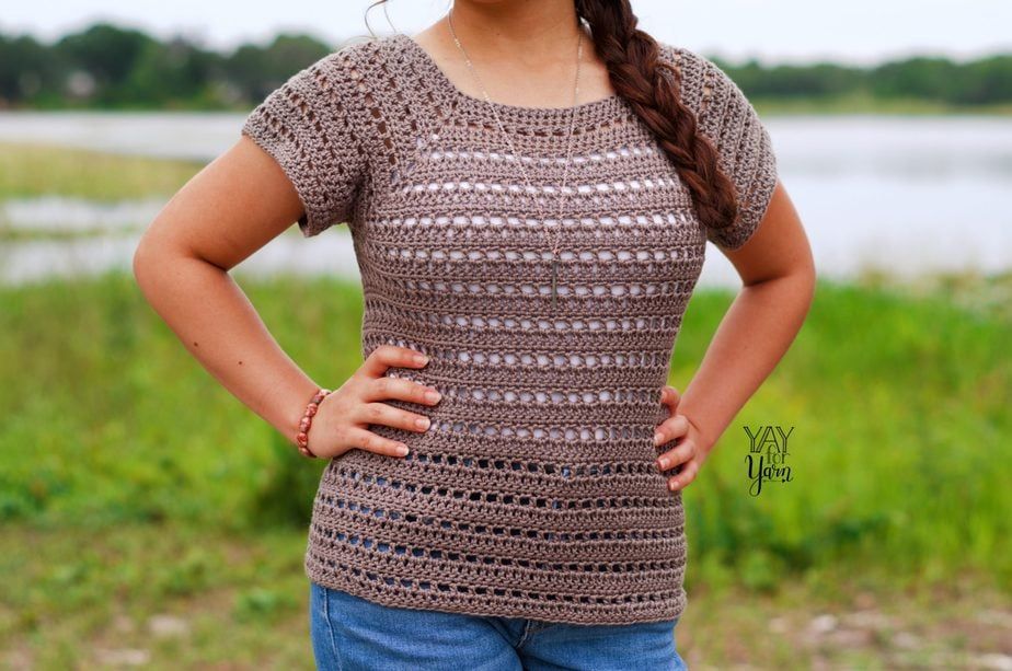 woman standing with hands on hips, wearing crochet summer tee in front of lake