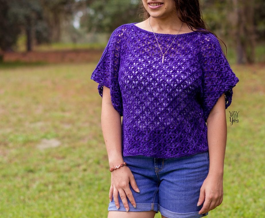 woman wearing dark blue / purple lace tee with wide sleeves, white tank, and jean shorts