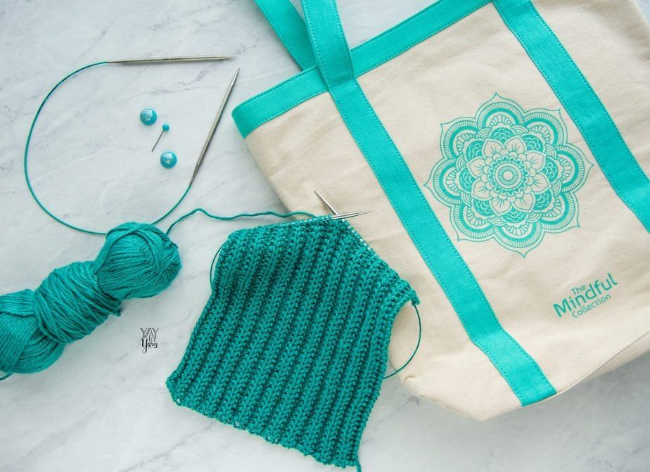 cream canvas tote with teal accents on white marble with teal knitting project