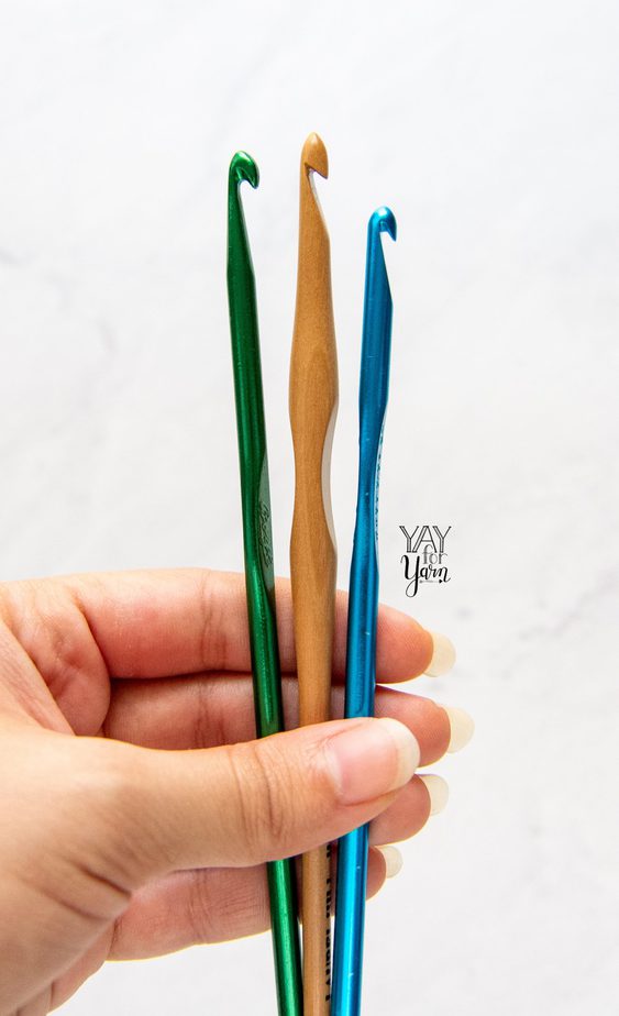 hand holding a boye hook, laurel hill hook, and susan bates hook for comparison - side view