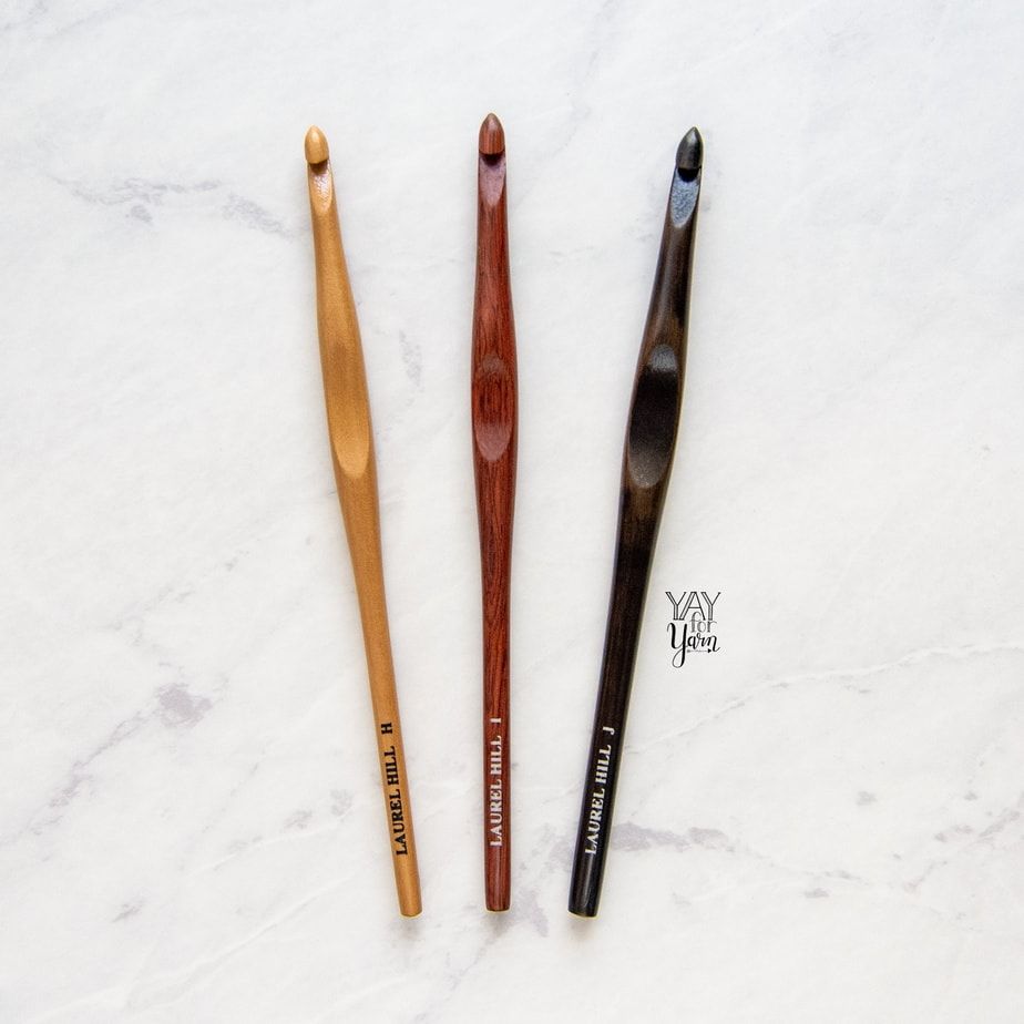 light, medium and dark wood crochet hooks on white marble