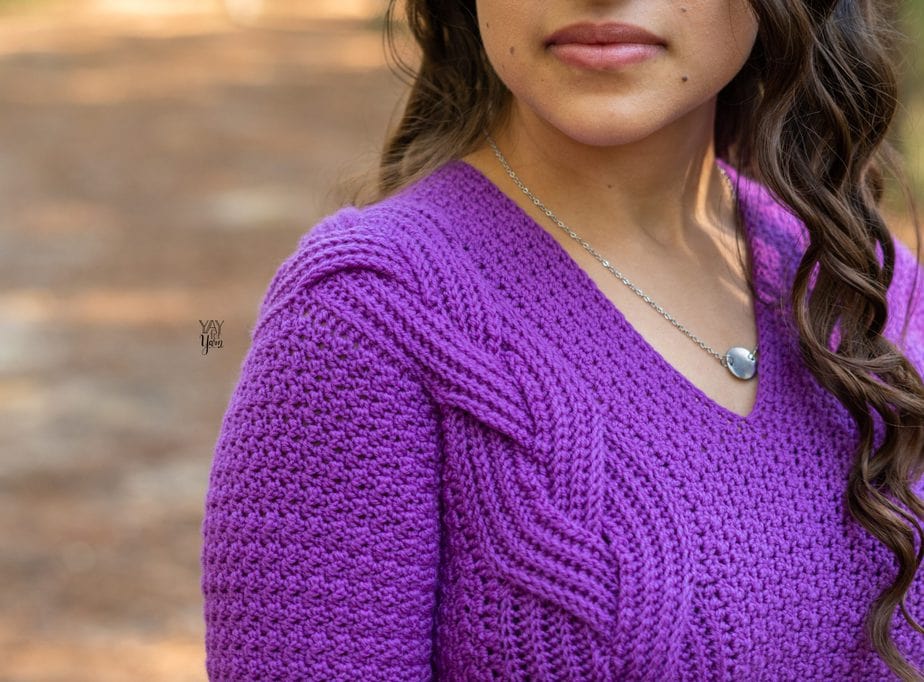 closeup of shoulder area on intertwine pullover crochet pattern, purple sweater with large braided cable on one side