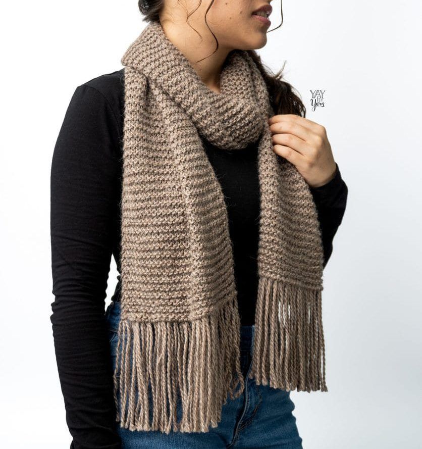 girl wearing black long sleeve tee shirt and chunky light brown knit scarf with fringe
